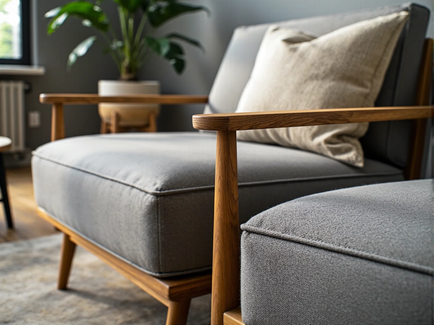 Szary fotel wypoczynkowy z drewnianymi podłokietnikami i pufą